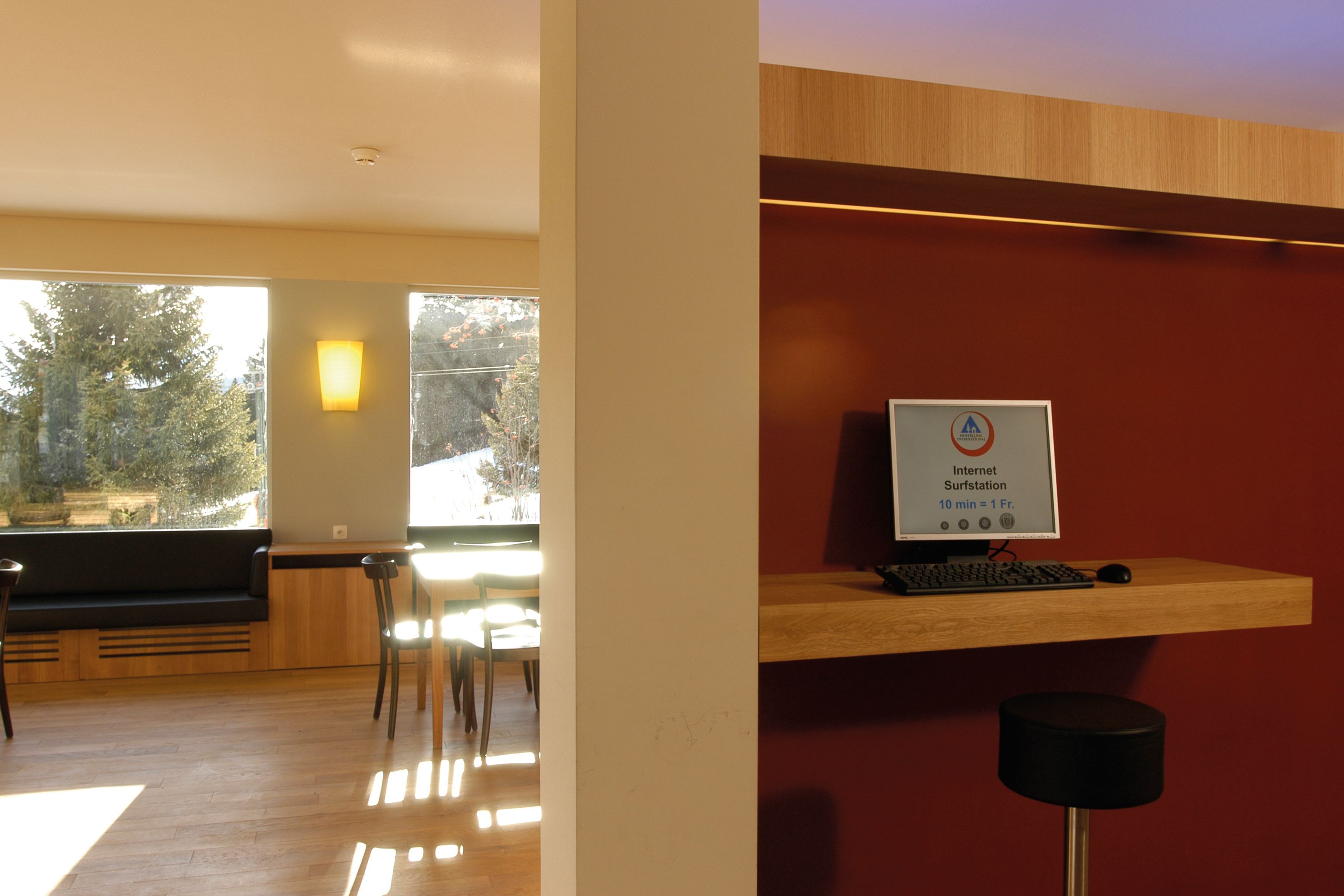 Une pièce moderne équipée d’un bureau en bois, d’un ordinateur et d’un panneau indiquant un poste de navigation sur Internet, avec un temps d’attente de 10 minutes.