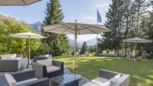Un patio con mobiliario de mimbre, sombrillas para el exterior y una vista panorámica de las montañas.