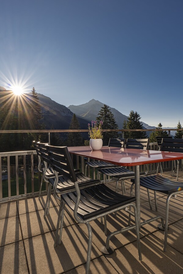 Un patio con mesa y sillas, con vistas a un paisaje montañoso.