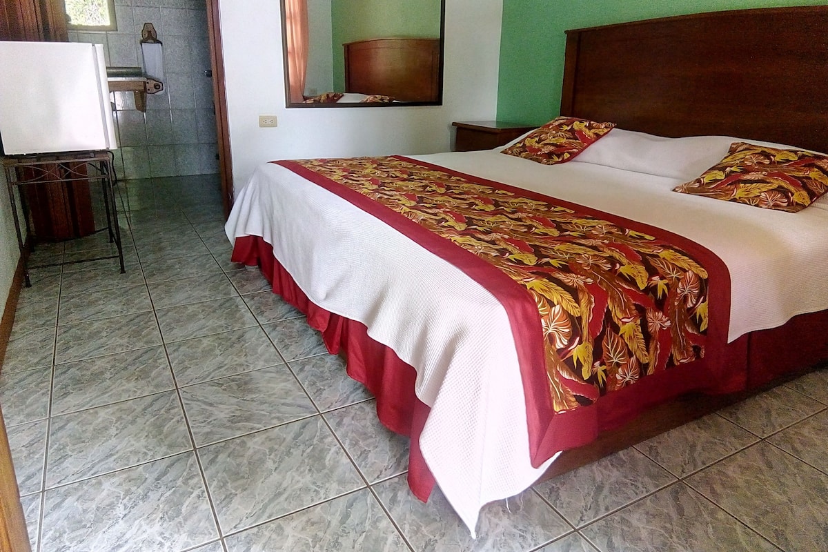 Una habitación de hotel con una cama, una mesita de noche, un espejo y una ventana.