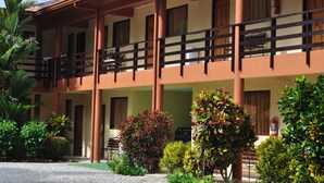 A hotel with a covered outdoor seating area, multiple balconies, and a variety of greenery. - Hotel Alkamar (Cóbano)
