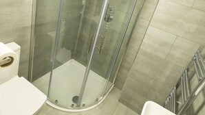 Une salle de bain moderne avec une douche à parois de verre, un lavabo blanc et des toilettes.