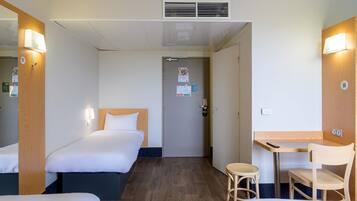 A hotel room with two beds, a desk, a chair, and a small table.