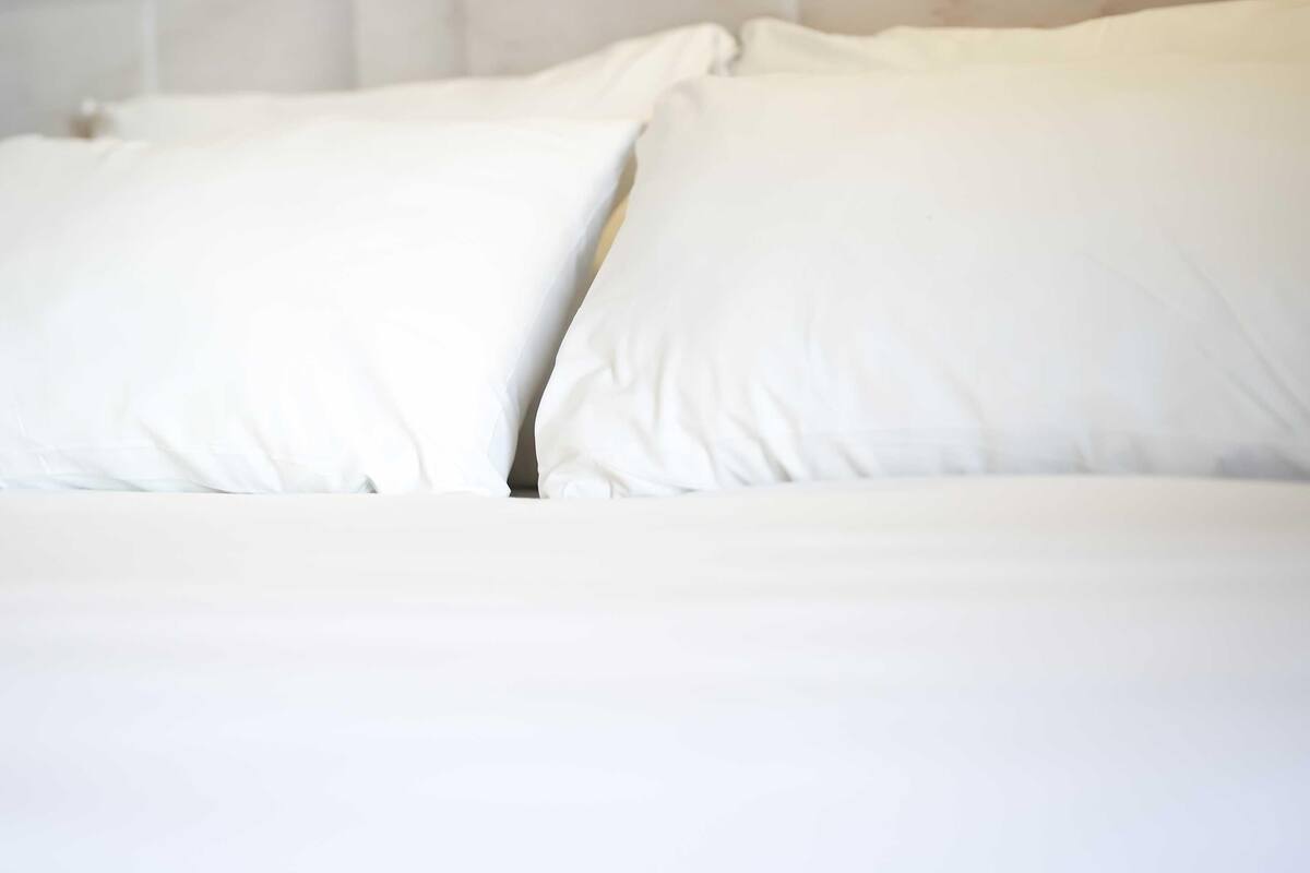 A bed with white bedding and pillows.