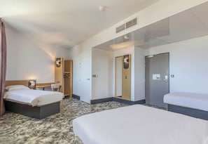 Une chambre d’hôtel avec deux lits, un bureau, une chaise, une armoire et un miroir.