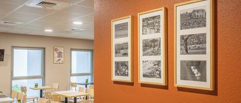 A room with tables and chairs, a bulletin board, and framed pictures on the wall.