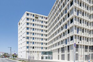 Un edificio moderno con fachada de entramado, varias ventanas y un cartel llamativo en la parte superior.