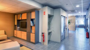 A hotel lobby with a reception desk, seating area, and a fire extinguisher. - B&B HOTEL Marseille Les ports (Marseille)