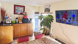 A kitchen with wooden cabinets, a dining table, and a large potted plant. - Budget Inn (Northport)