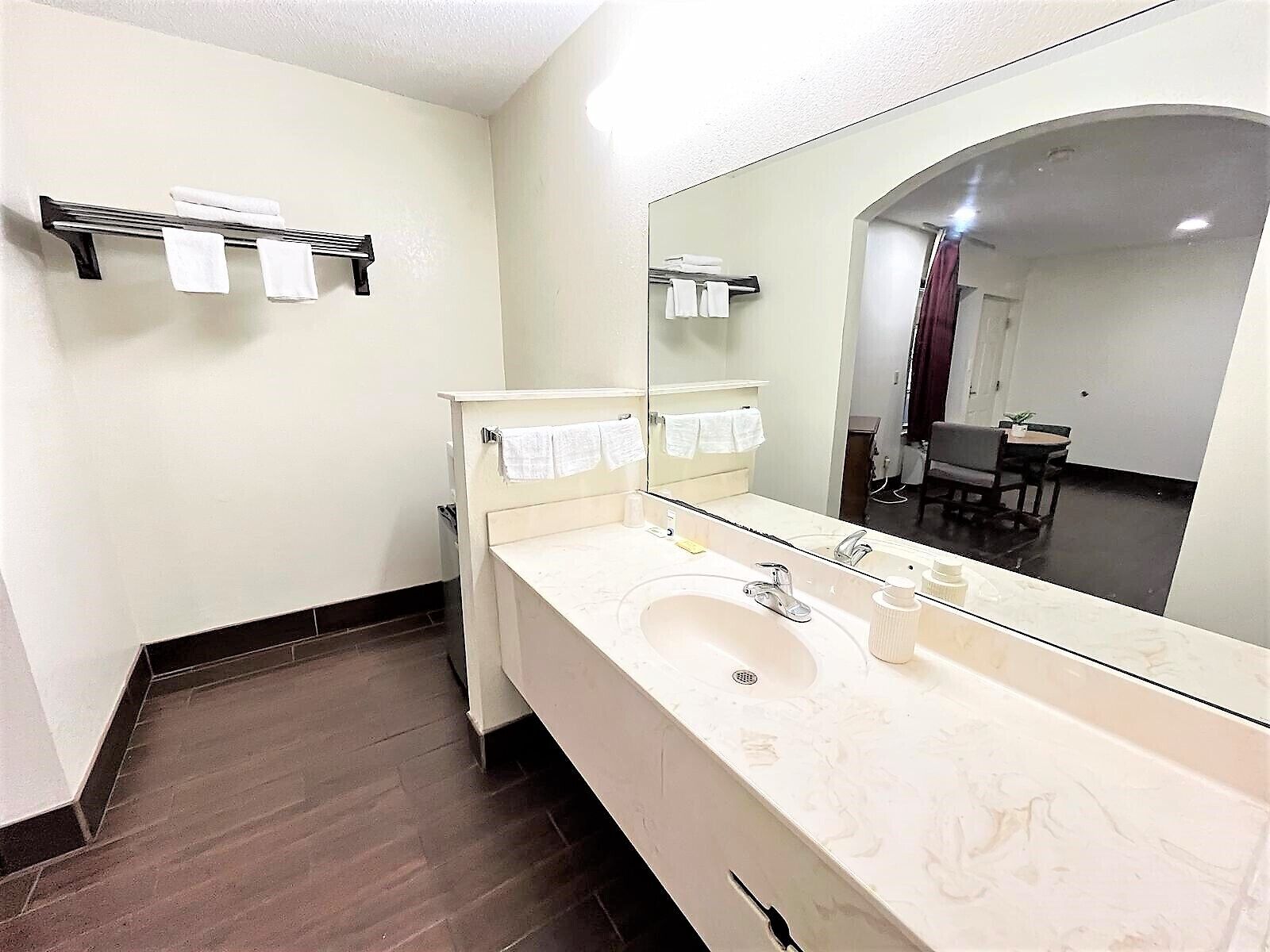 A bathroom with a large mirror, a sink, and a towel rack.