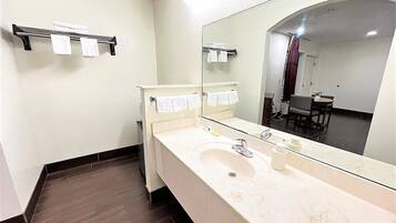 A bathroom with a large mirror, a sink, and a towel rack.