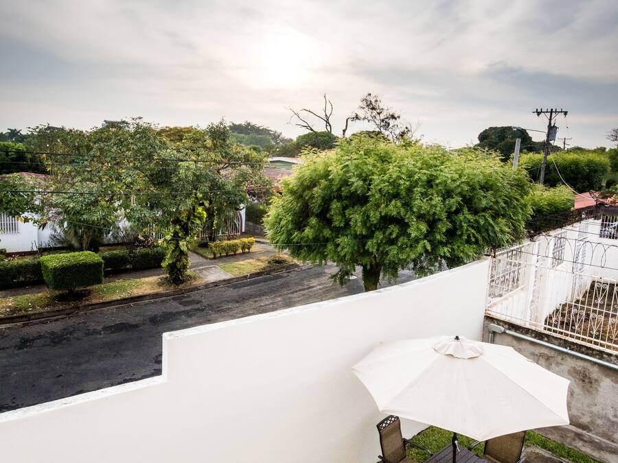 A patio with a table and chairs, surrounded by a white wall and a grassy area.