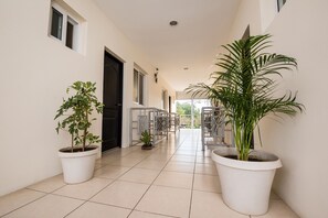 A hallway with potted plants, a tiled floor, and a view of the outside. - Verona Aparthotel (Managua)