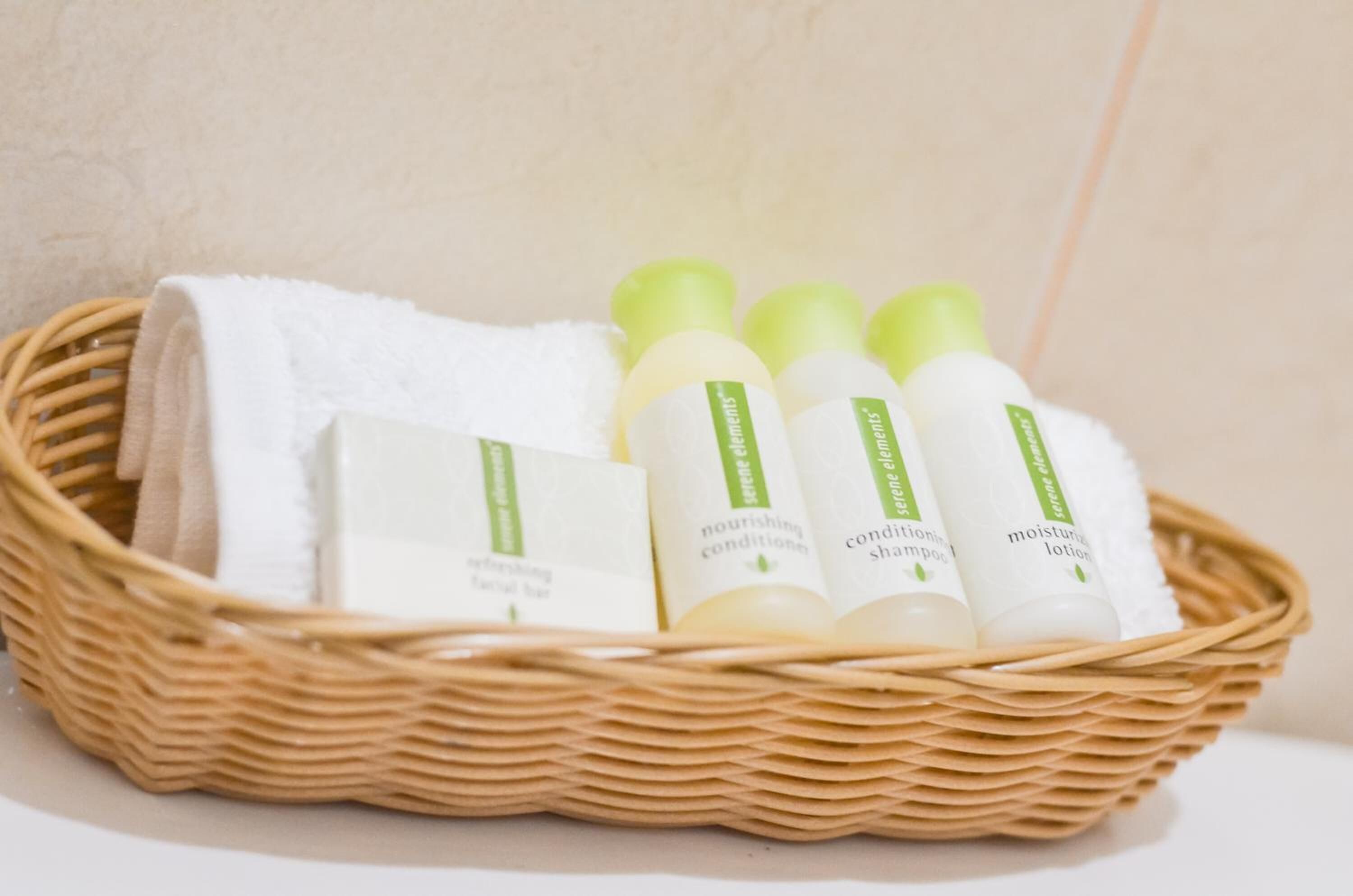 A wicker basket containing a white towel, three bottles of skincare products, and a box labeled "nourishing conditioner".