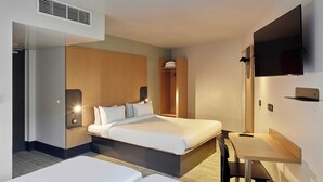 A hotel room with two beds, a desk, a TV, and a wardrobe.