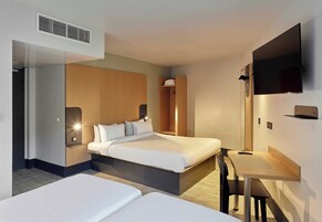 Une chambre d’hôtel avec deux lits, un bureau, une télévision et une armoire.