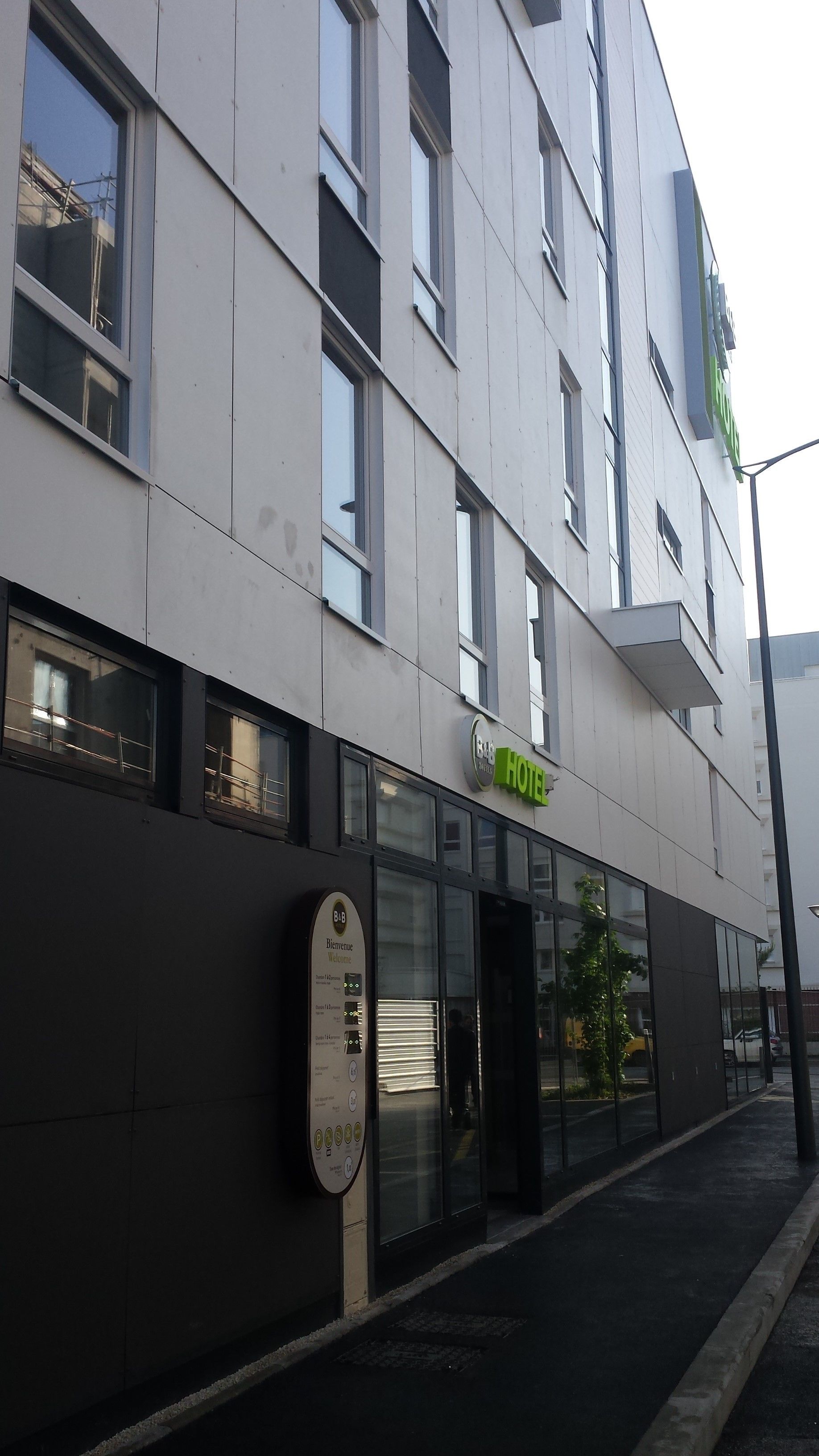 A modern hotel facade with a prominent green sign indicating it is a hotel.