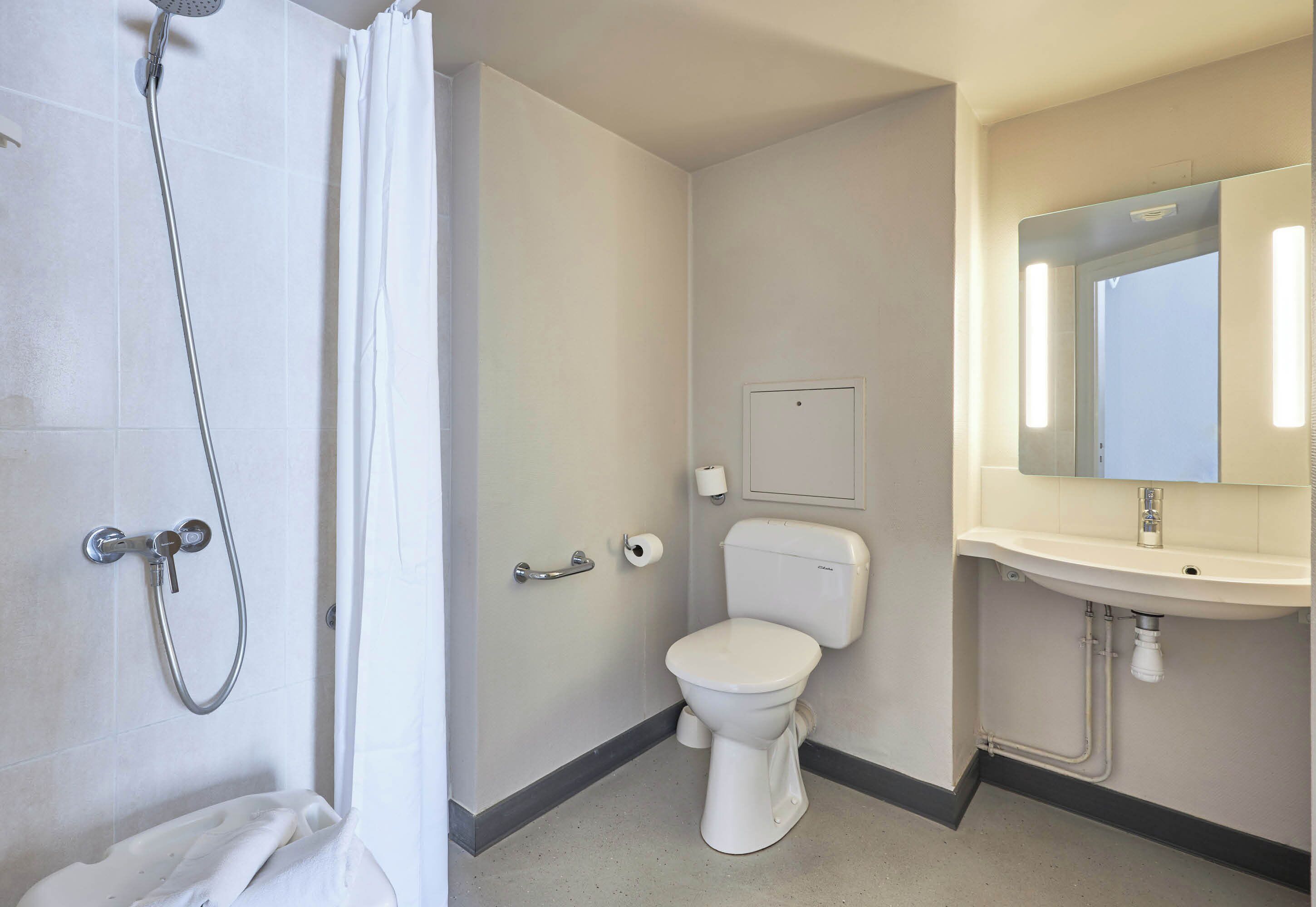 Une salle de bain équipée d’une douche, de toilettes, d’un lavabo et d’un miroir.
