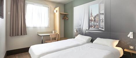 A hotel room with two beds, a desk, a chair, and a large window with a cityscape view.