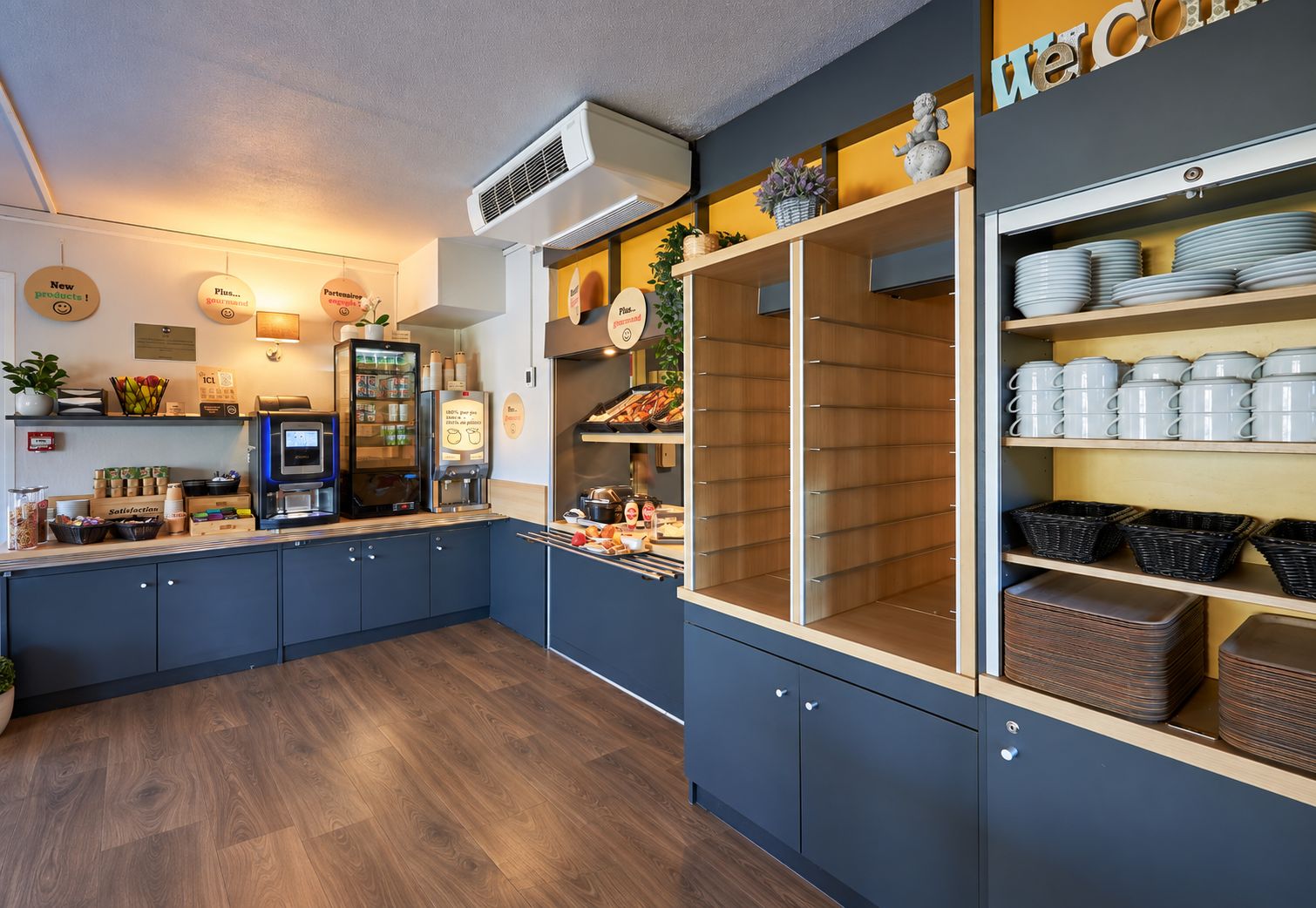 A modern kitchen with a coffee station, a refrigerator, and a welcome sign.
