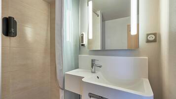 Un baño moderno con ducha, lavamanos y espejo.
