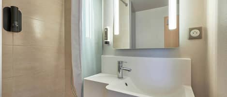 A modern bathroom with a shower, a sink, and a mirror.