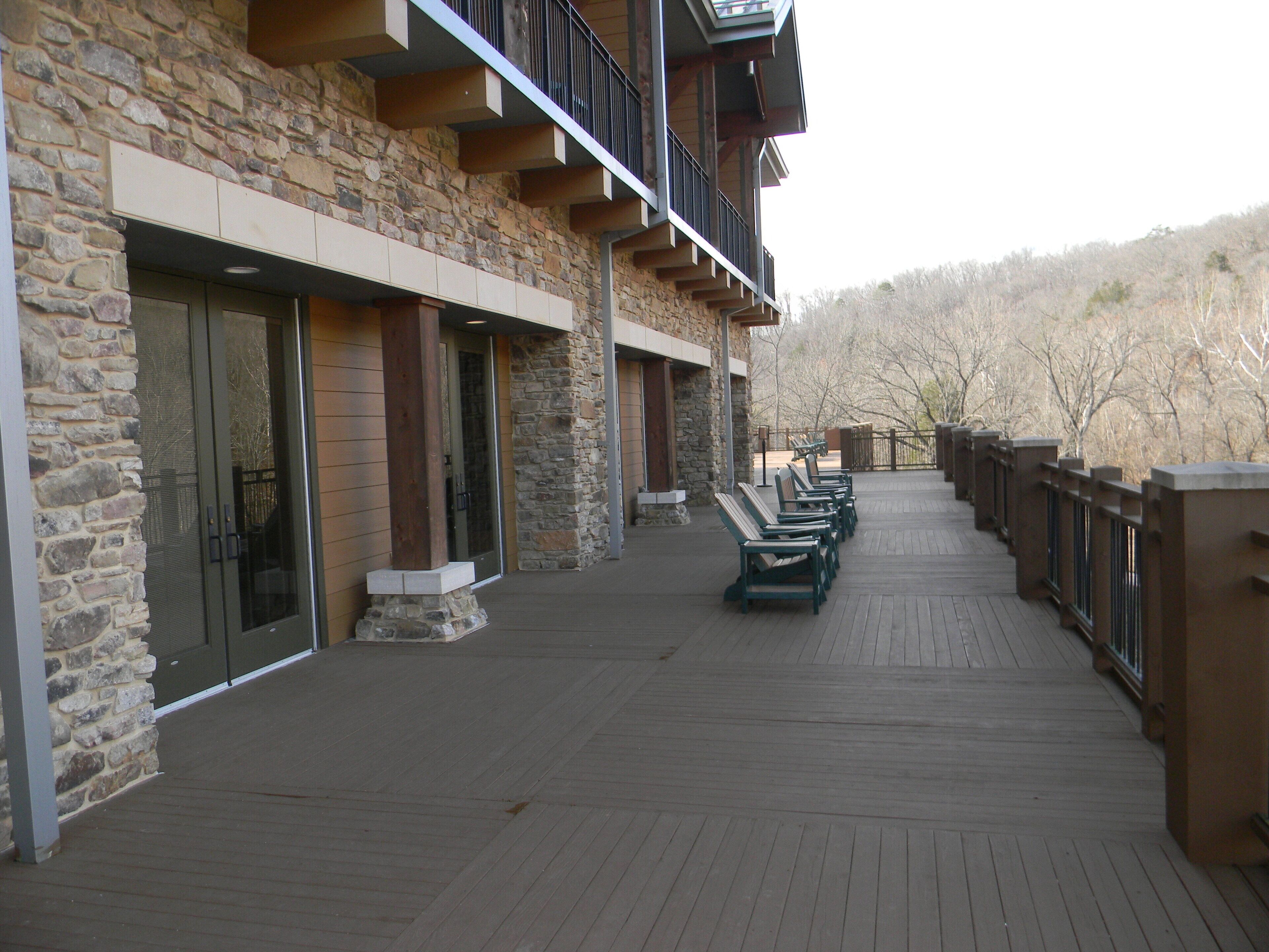 A building with a stone facade, wooden deck, and outdoor seating.
