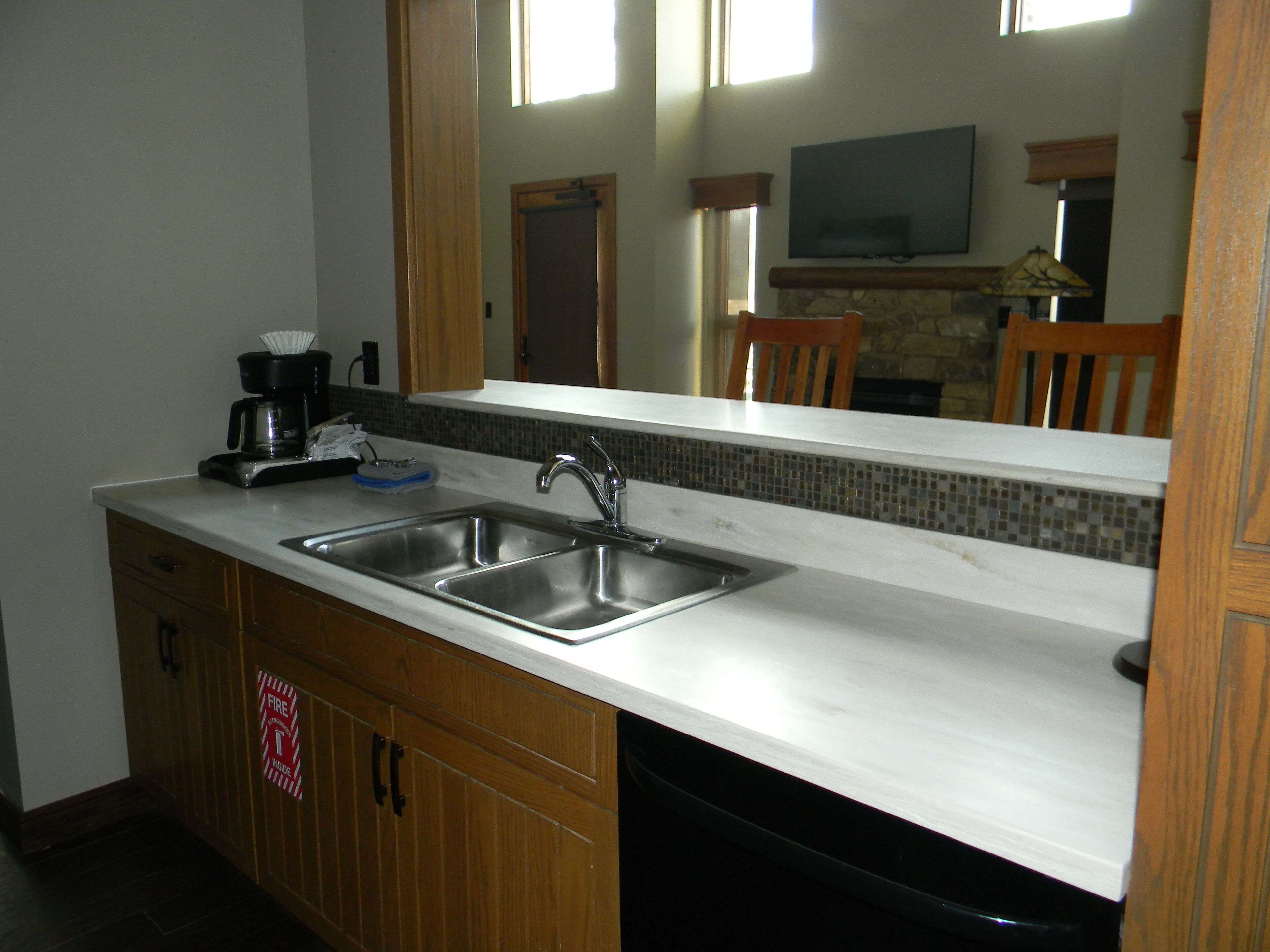 A kitchen with two stainless steel sinks, a coffee maker, and a microwave.