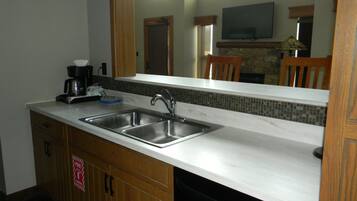 A kitchen with two stainless steel sinks, a coffee maker, and a microwave.