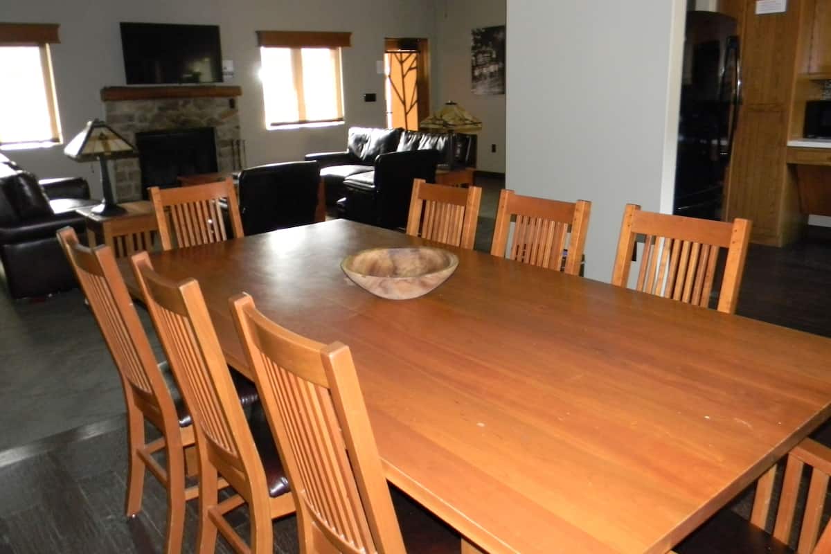 A dining area with a wooden table and chairs, a fireplace, and a kitchen area with cabinets.