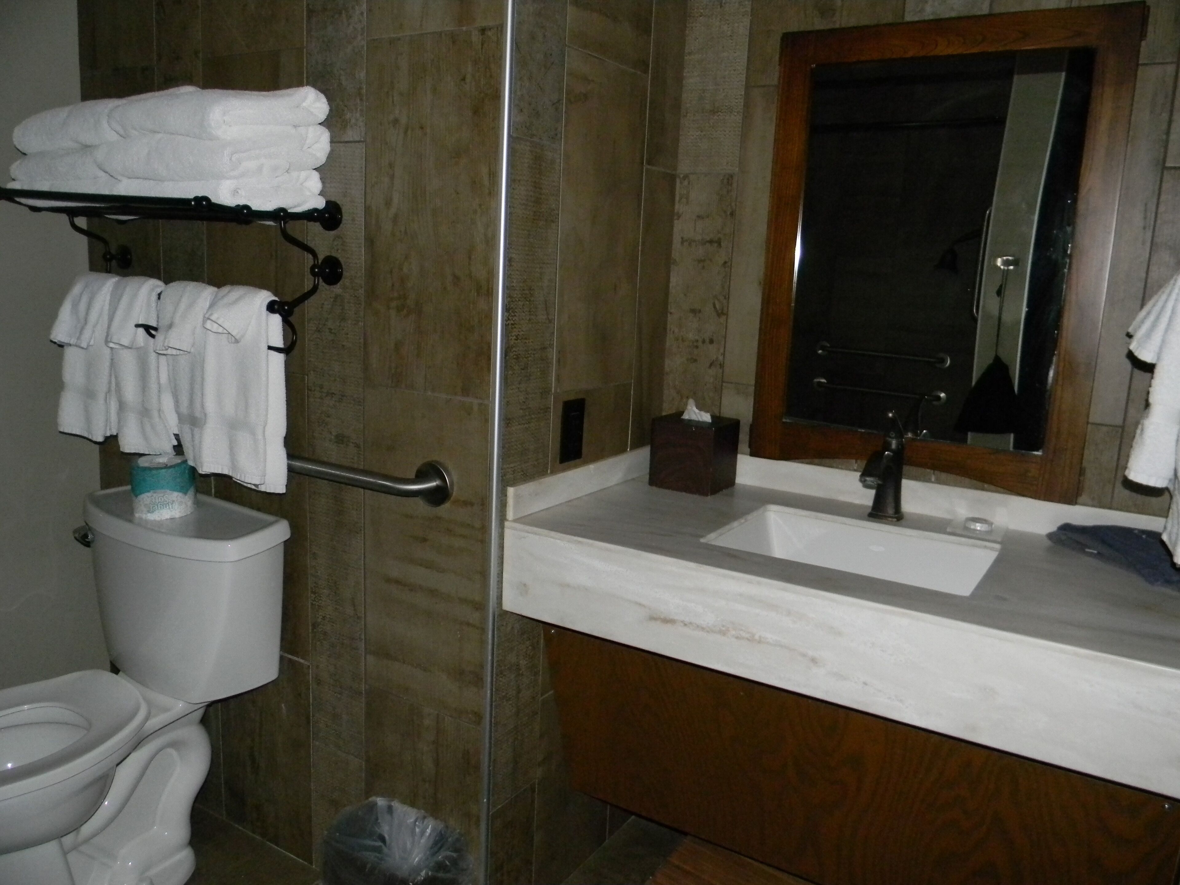 Un baño con inodoro, lavamanos, espejo y toallero.