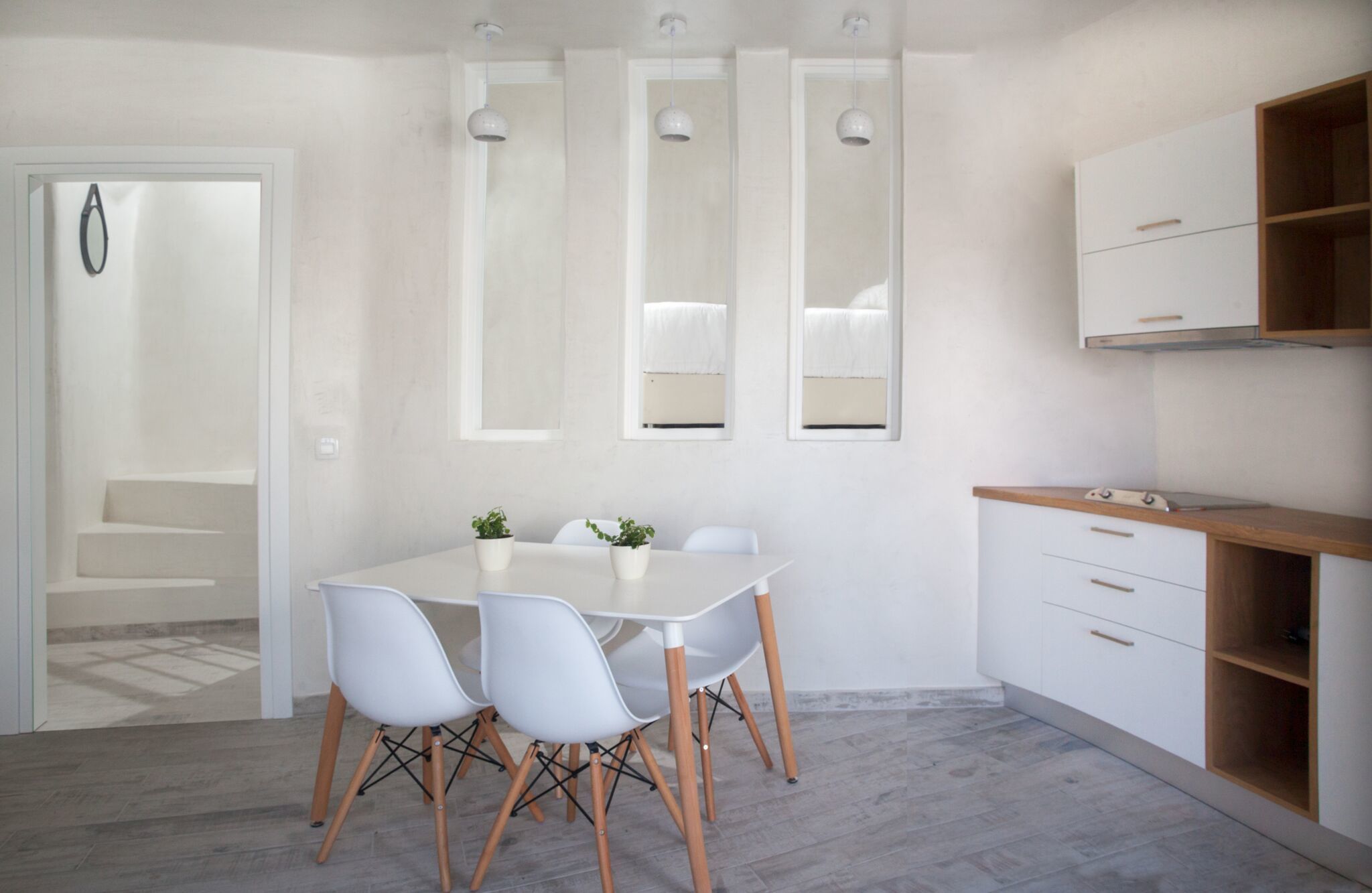 A modern kitchen with white cabinets, a wooden countertop, and a dining area with a white table and chairs.