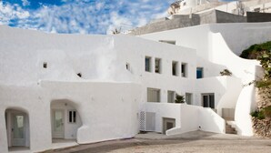A white building with multiple windows and a blue dome. - Spilies by Thireas (Santorini)