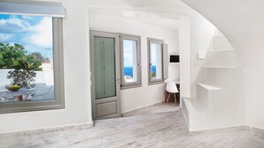 A modern interior with a view of the sea, a staircase, and a small seating area. - Spilies by Thireas (Santorini)