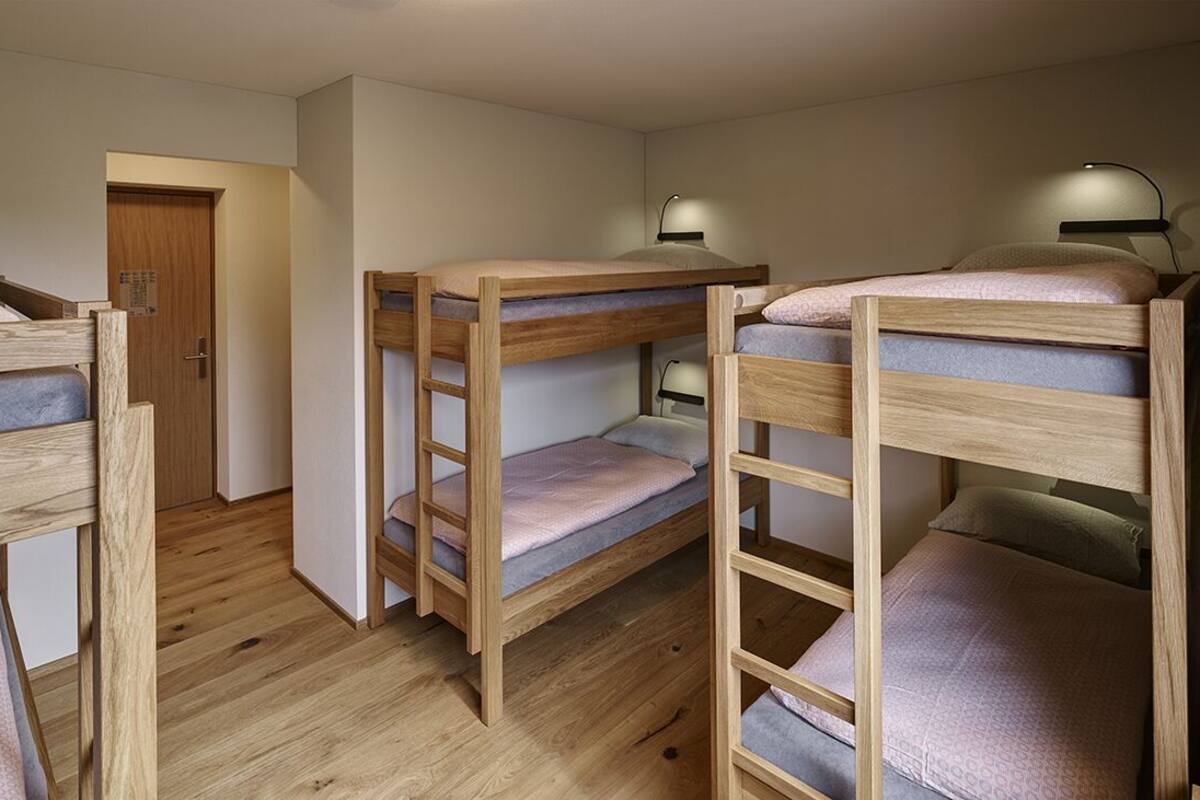 Een kamer met stapelbedden, houten vloeren en bedlampjes.