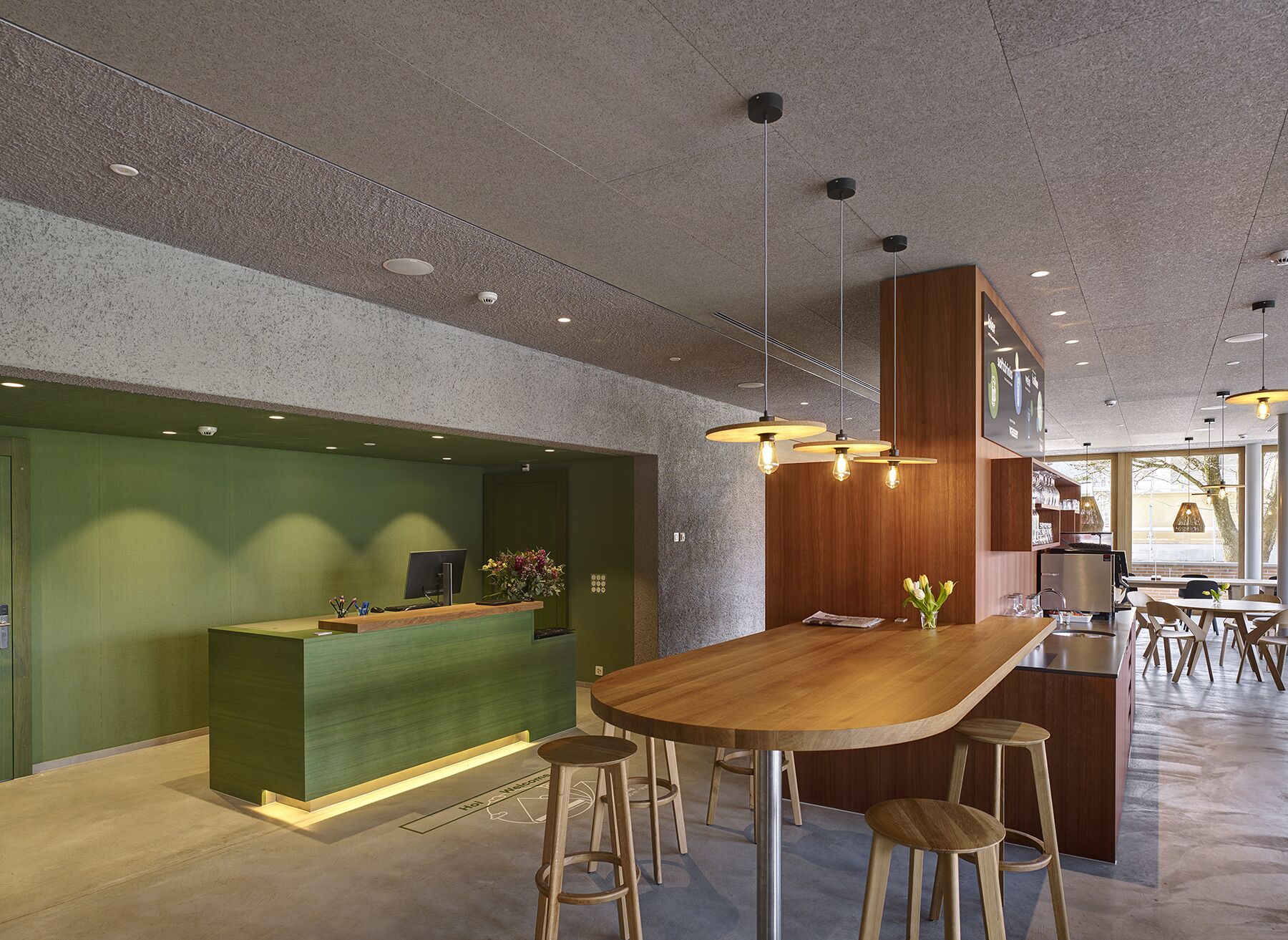 A modern reception area with a wooden reception desk, bar stools, and a large dining table.