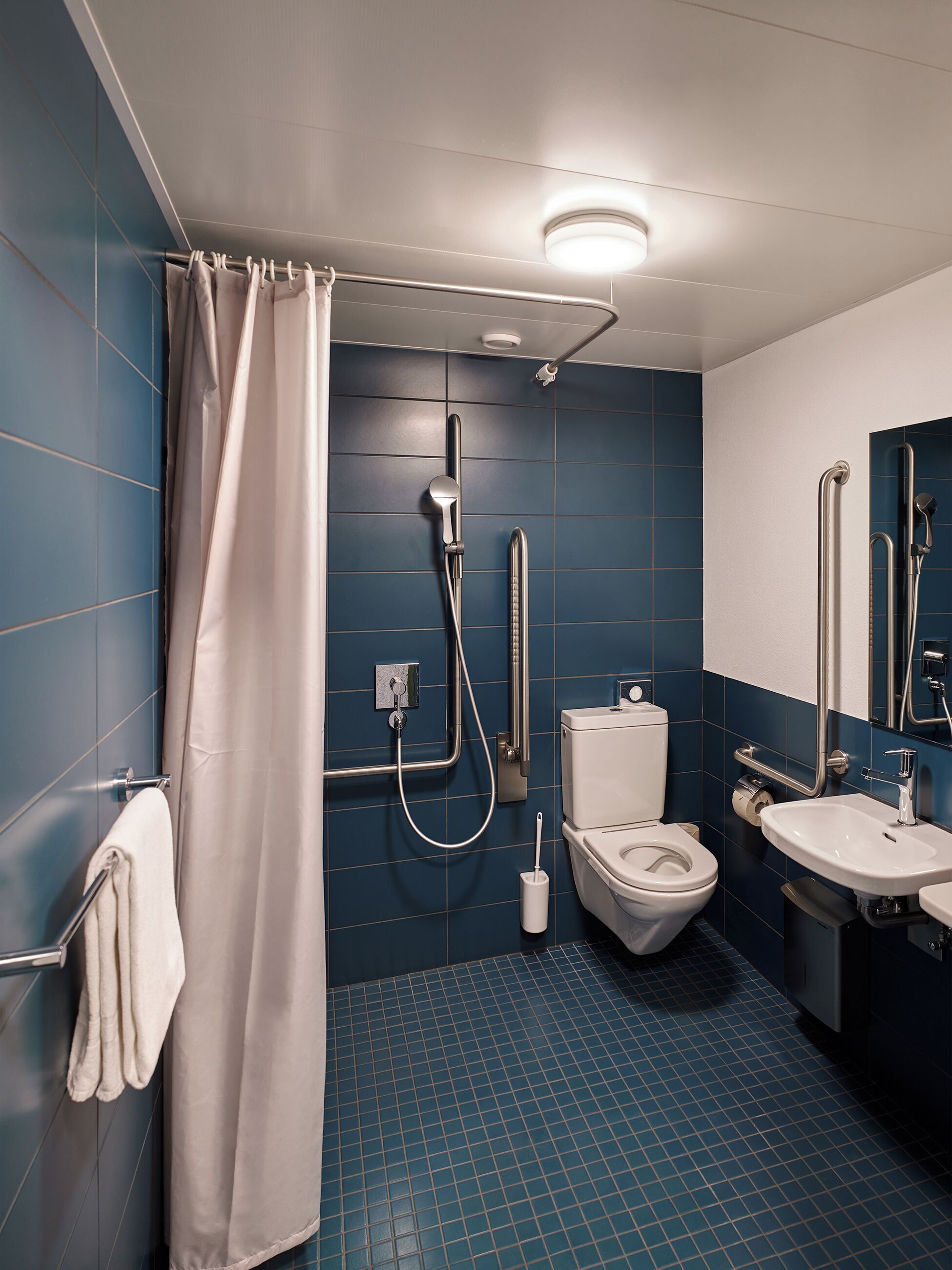 A modern bathroom with a shower, toilet, and sink.