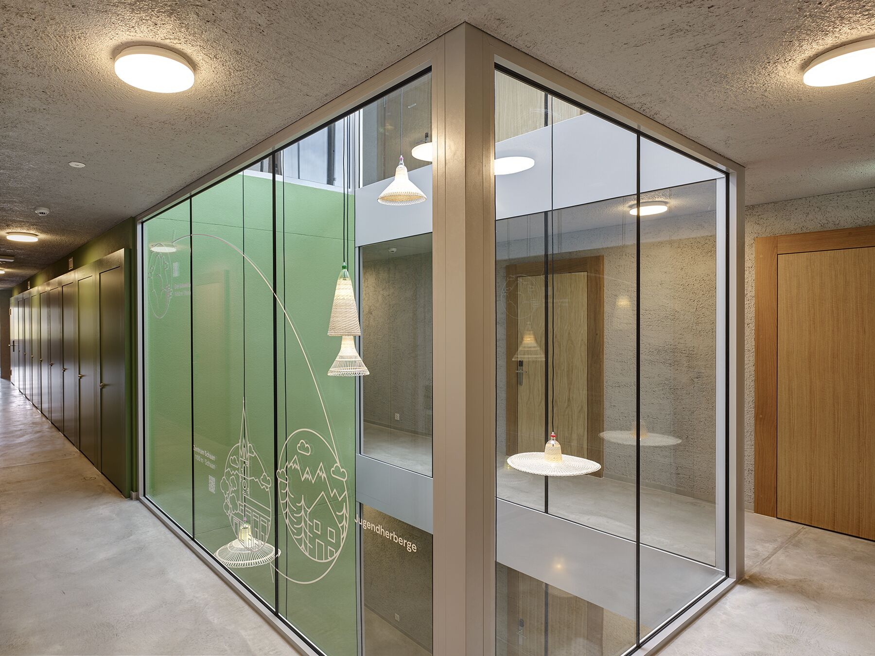 A corridor with glass walls, wooden doors, and pendant lighting.