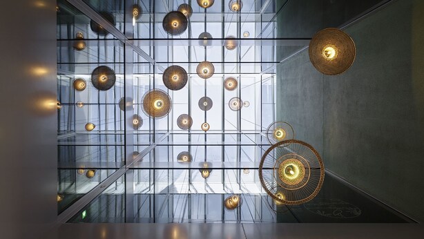Een modern interieur met een raster van hangende bolvormige lampen en een grote geweven verlichtingsarmatuur.