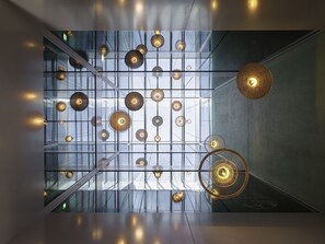 Un interior moderno con una cuadrícula de luces esféricas colgantes y una gran lámpara de fibra trenzada.