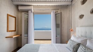 Ein Schlafzimmer mit Bett, Meerblick und einer Holzhilfe.