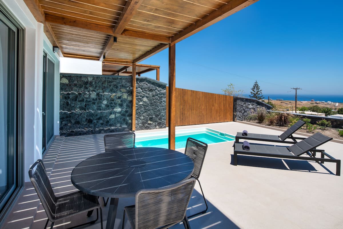 Un espacio al aire libre techado con piscina, sillones de descanso y una mesa con sillas.