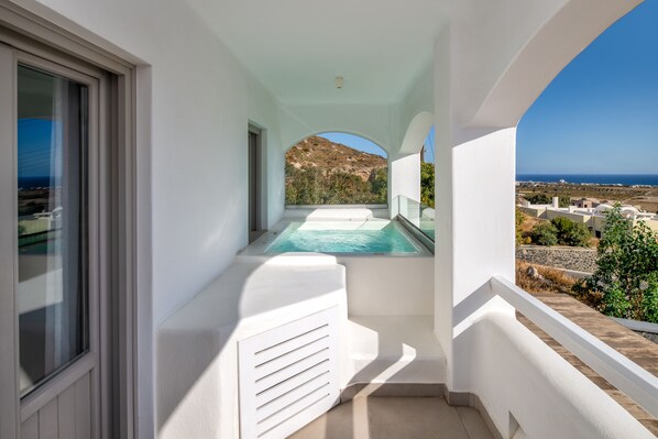 A balcony with a view of a pool and a mountainous landscape.