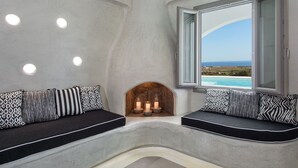 Ein gemütlicher Sitzbereich mit Kamin, einem großen Fenster mit freiem Meerblick und einer Decke mit Einbaustrahlern.