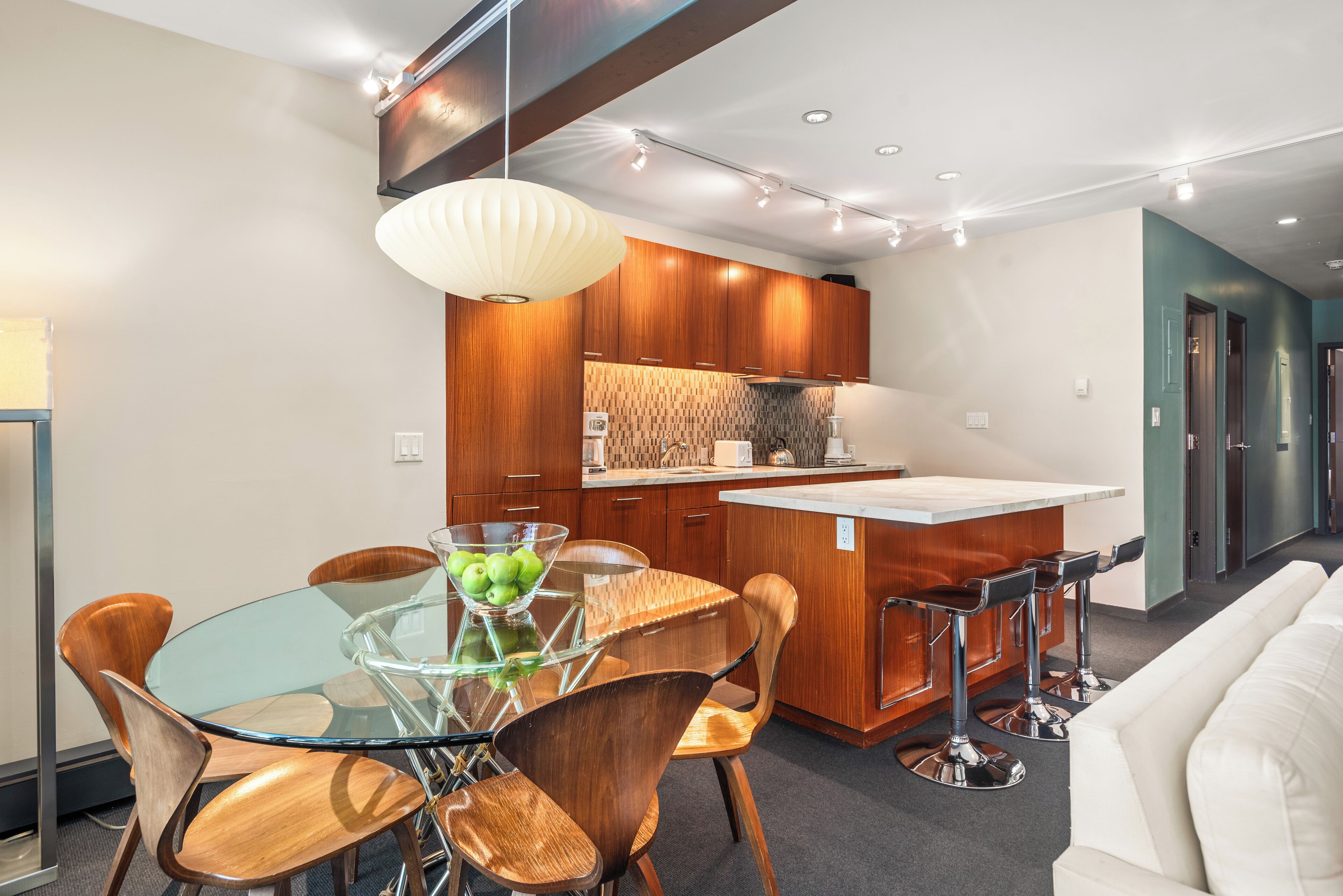 A modern kitchen with wooden cabinets, a glass dining table, and a white island.