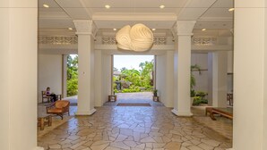 A spacious lobby with a stone floor, a large decorative light fixture, and a view of a tropical garden. - Kaanapali Shores Studio 742 Studio Bedroom Condo by RedAwning (Lahaina)