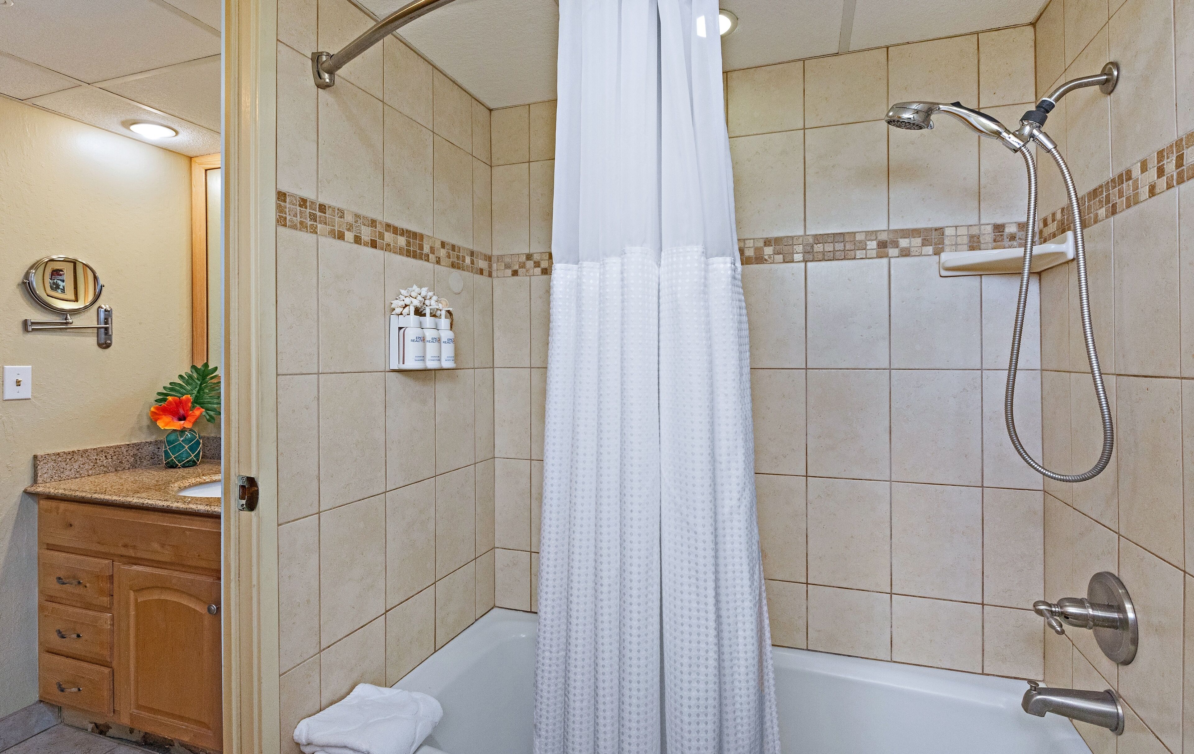 A bathroom with a bathtub, shower, and a vanity with a mirror and towel rack.