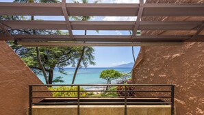 A balcony with a view of the ocean and palm trees.