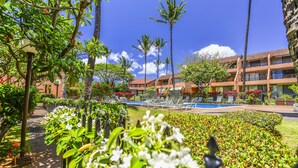 A resort with a pool area, palm trees, and a well-maintained garden.