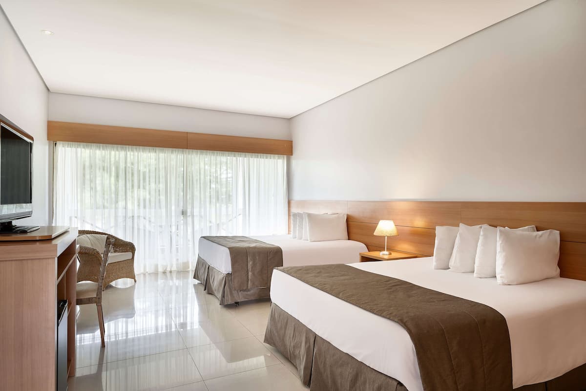 Une chambre d’hôtel avec deux lits, un bureau et une télévision.
